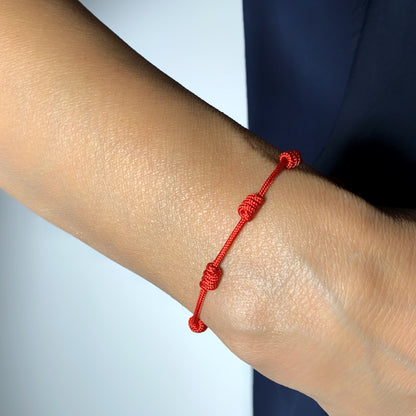 Pulsera roja de 7 nudos puesta en la muñeca de una mujer