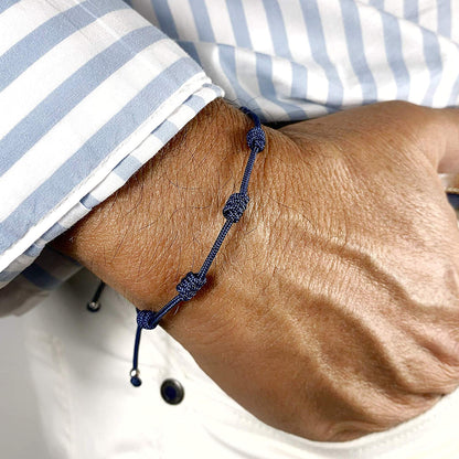 Pulsera azul marino de 7 nudos puesta en la muñeca de un hombre